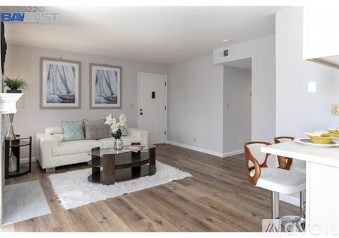 A living room with a white couch, a coffee table, and a dining table with chairs.
