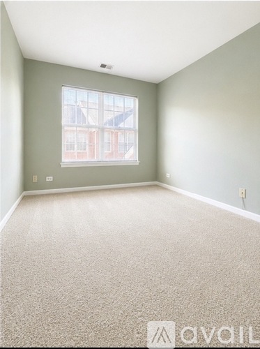 A room with a carpeted floor and a window showing a building outside.
