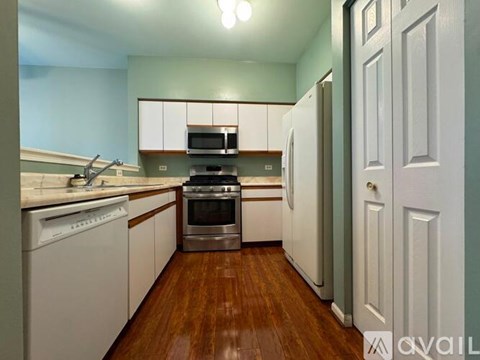 A kitchen with white cabinets and a wooden floor.