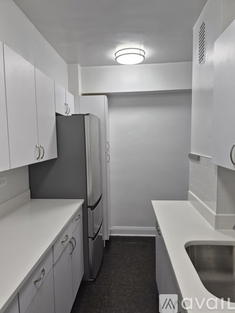 A kitchen with white cabinets and a black refrigerator.