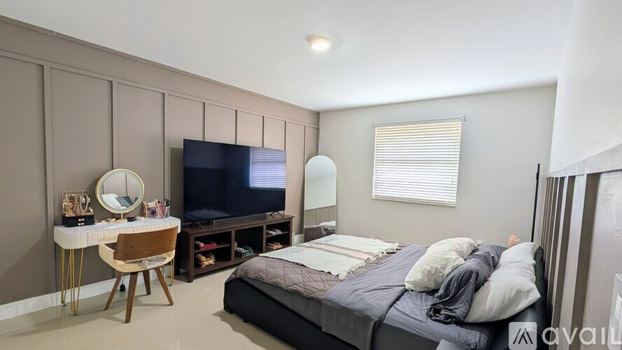 A bedroom with a bed, desk, and television.