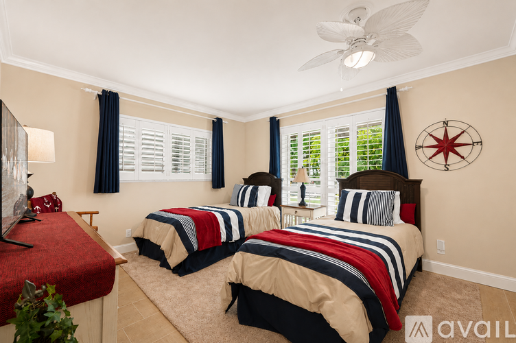 A bedroom with two beds and a ceiling fan.