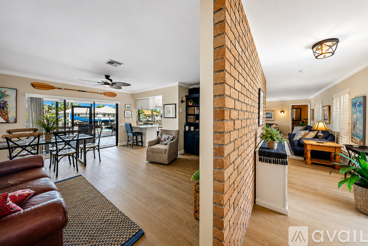 A living room with a brick wall and a dining area with a table and chairs.