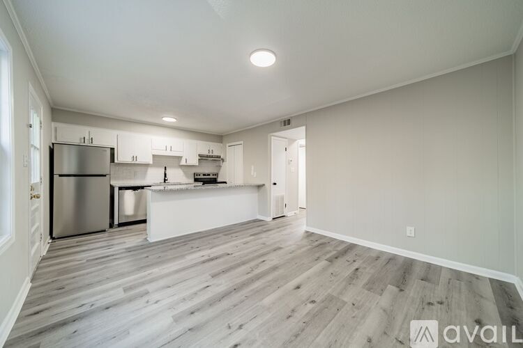 A kitchen with white cabinets and a wooden floor.
