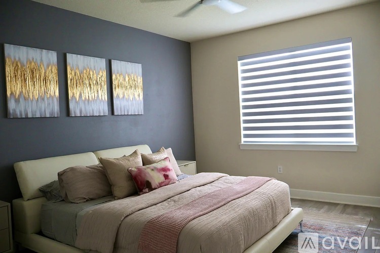 A bedroom with a bed, pillows, and a painting on the wall.