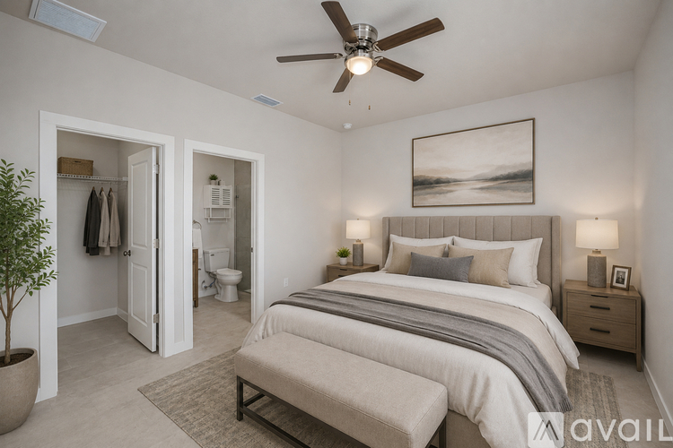 A bedroom with a large bed, a bench, and a ceiling fan.