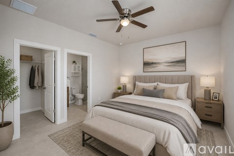 A bedroom with a large bed, a bench, and a ceiling fan.