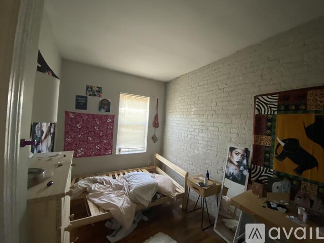 A room with a bed, a desk, and a poster on the wall.