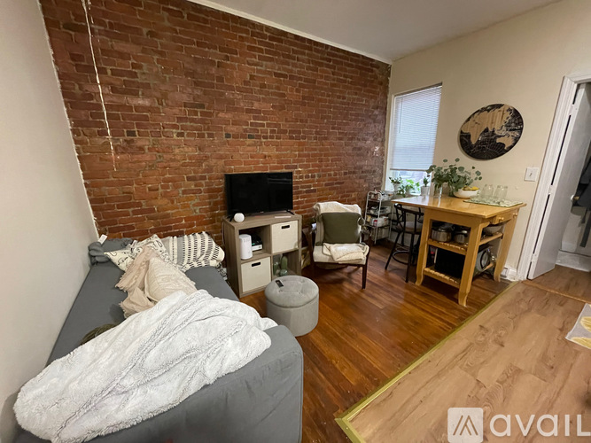 A bedroom with a brick wall and a grey bedspread.