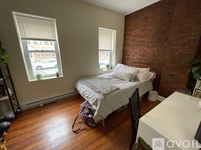 A bedroom with a bed, a chair, and a window with blinds.