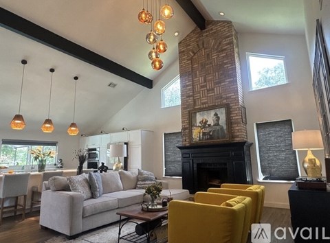 A living room with a grey couch, yellow armchair, and a fireplace with a painting above it.