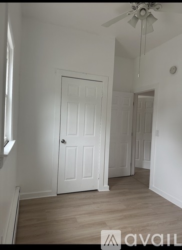 A room with a white door and a ceiling fan.