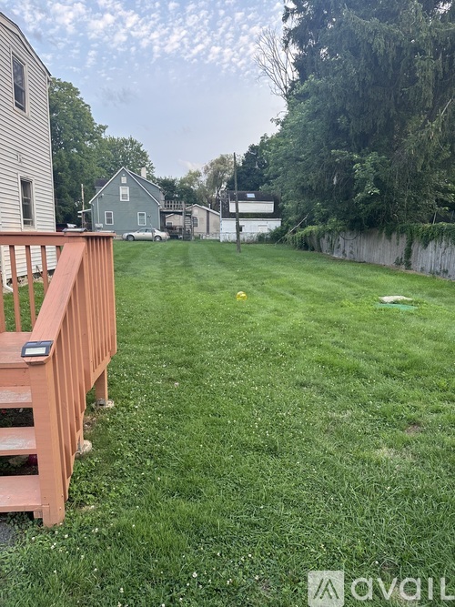 A backyard with a wooden deck and a green lawn.