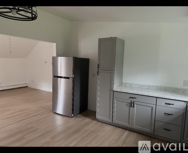 A kitchen with a stainless steel refrigerator and a cabinet with a marble countertop.