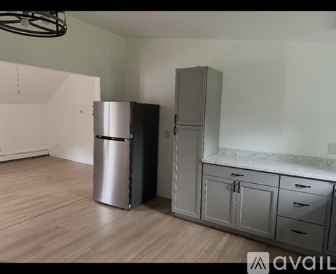A kitchen with a stainless steel refrigerator and a cabinet with a marble countertop.