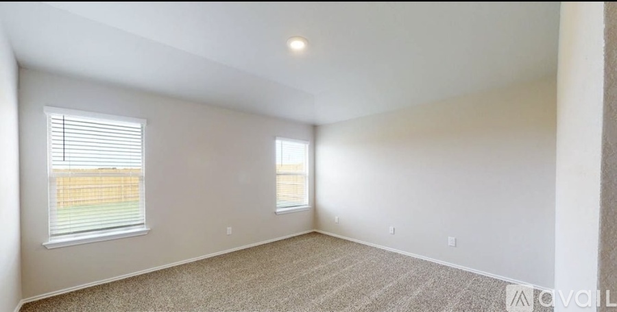 A spacious room with a window and carpeted floor.
