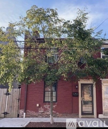 A tree in front of a red brick house.