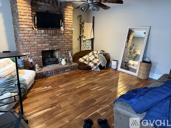 A living room with a brick fireplace and a ceiling fan.