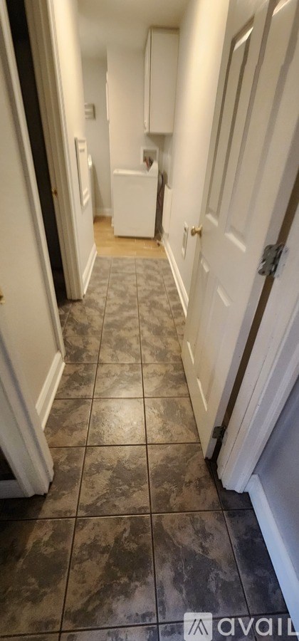 A hallway with a tiled floor and white walls.