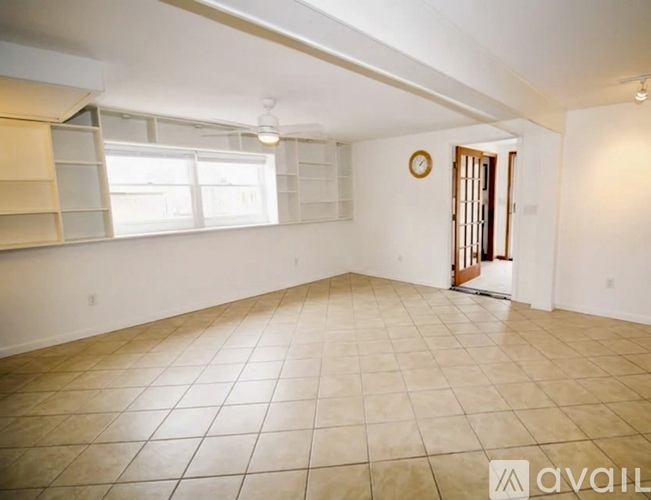 A spacious room with tiled flooring and a door on the right.