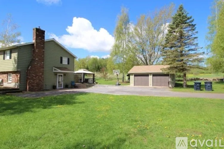 A house with a green lawn and trees in the background.