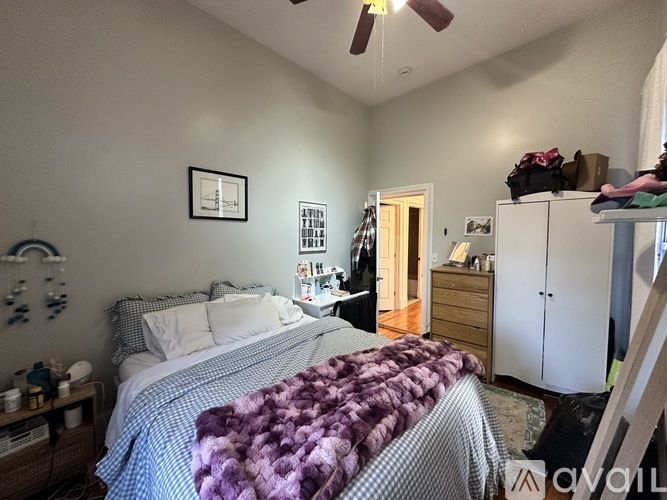 A bedroom with a bed, dresser, and ceiling fan.