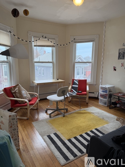 A living room with a red chair, a white chair, and a yellow rug.