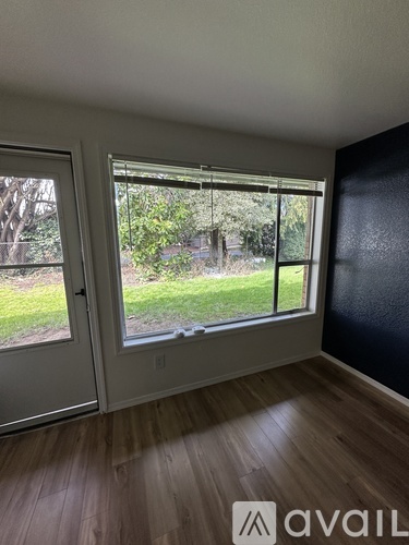A room with a large window and wooden flooring.