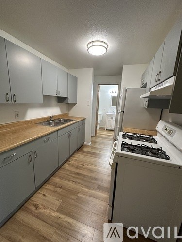 A kitchen with a wooden counter top and grey cabinets.