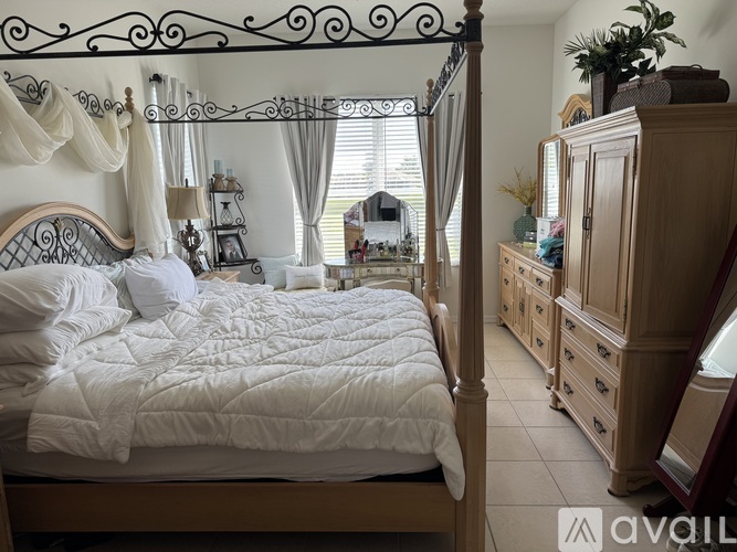 A bedroom with a four poster bed and a wooden dresser.