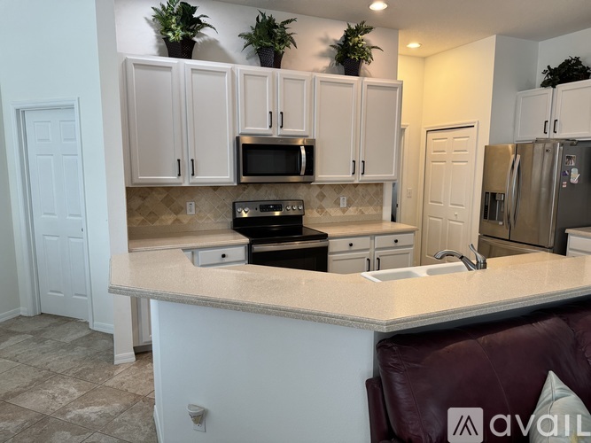 A kitchen with white cabinets and a marble countertop.