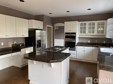 A kitchen with white cabinets and a black countertop.