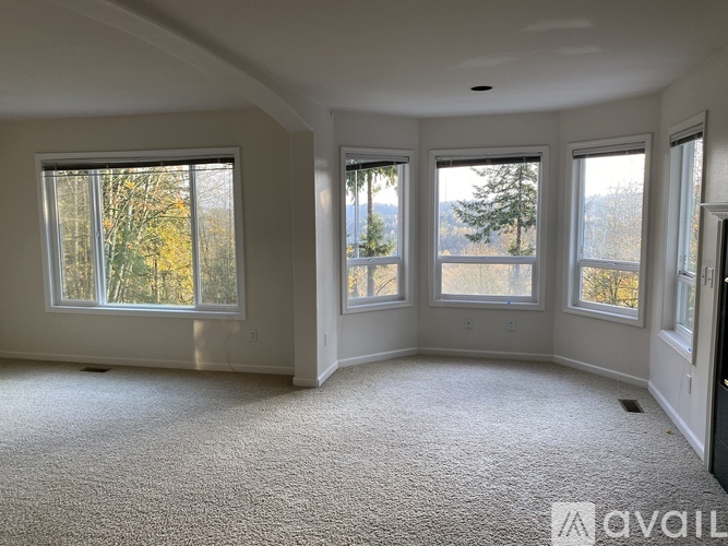 A spacious room with carpeted floor and large windows.