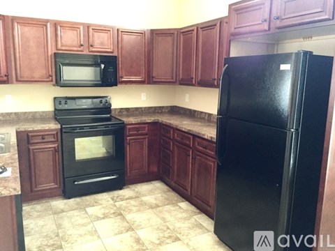 A kitchen with brown cabinets and a black refrigerator.