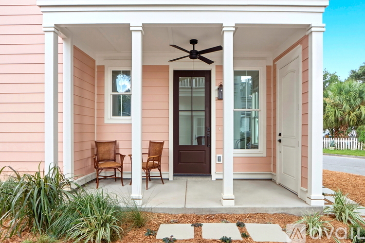 A pink house with a porch and two chairs.