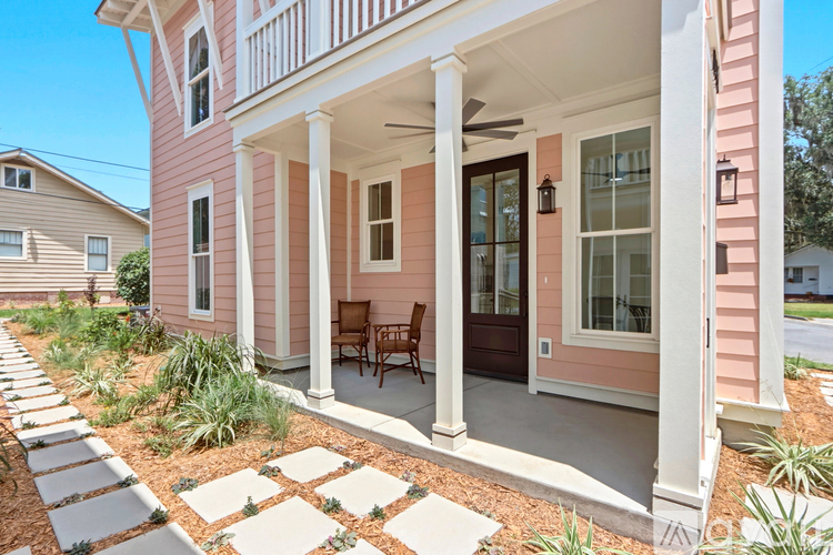 A pink house with a porch and a rock garden in front.