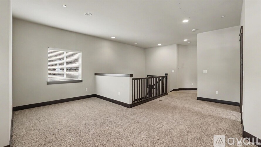 A spacious room with a carpeted floor and a window with blinds.