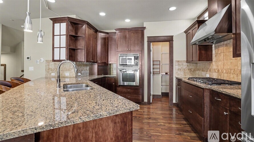 A kitchen with brown cabinets and a granite countertop.