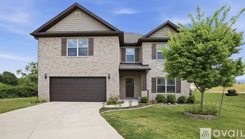 A house with a garage and a tree in front.