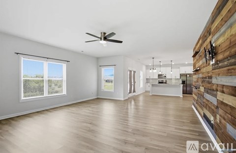 A spacious room with a ceiling fan and wooden flooring.
