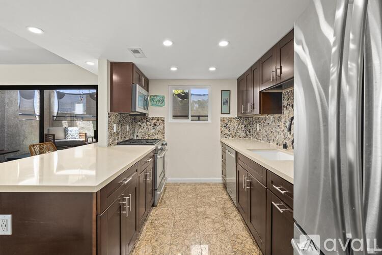 A kitchen with brown cabinets and a marble backsplash.