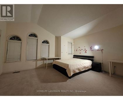 A bedroom with a bed, two chairs, and a window.
