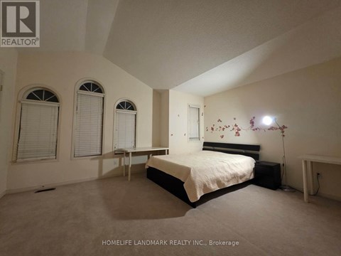 A bedroom with a bed, two chairs, and a window.