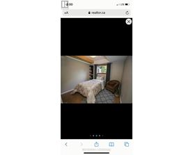 A bedroom with a bed covered in a beige blanket and a small dog bed next to the bed.