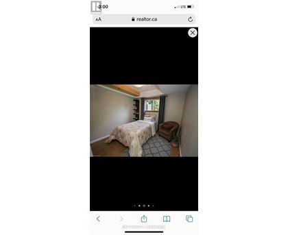 A bedroom with a bed covered in a beige blanket and a small dog bed next to the bed.
