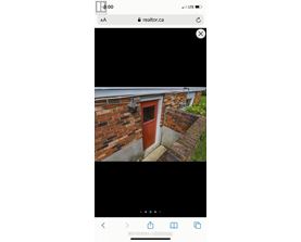 A red door is on a brick wall with a small window above it.