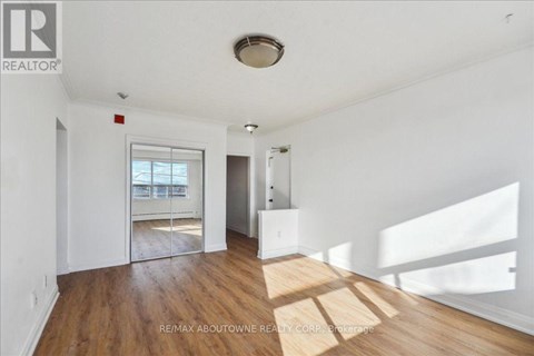 A room with wooden floors and white walls, with a window letting in natural light.