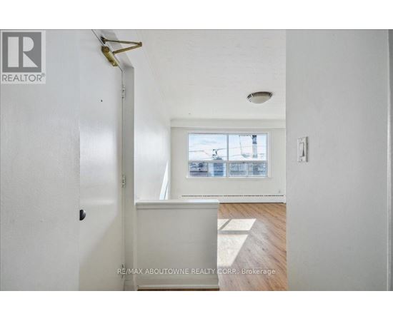 A white hallway with a door on the left and a window on the right.