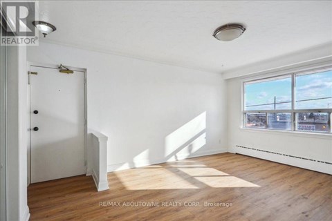 A room with a door and a window showing a view of a fence and other buildings.