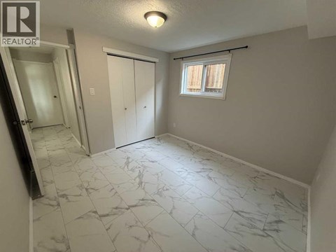 A room with marble flooring and a window with blinds.